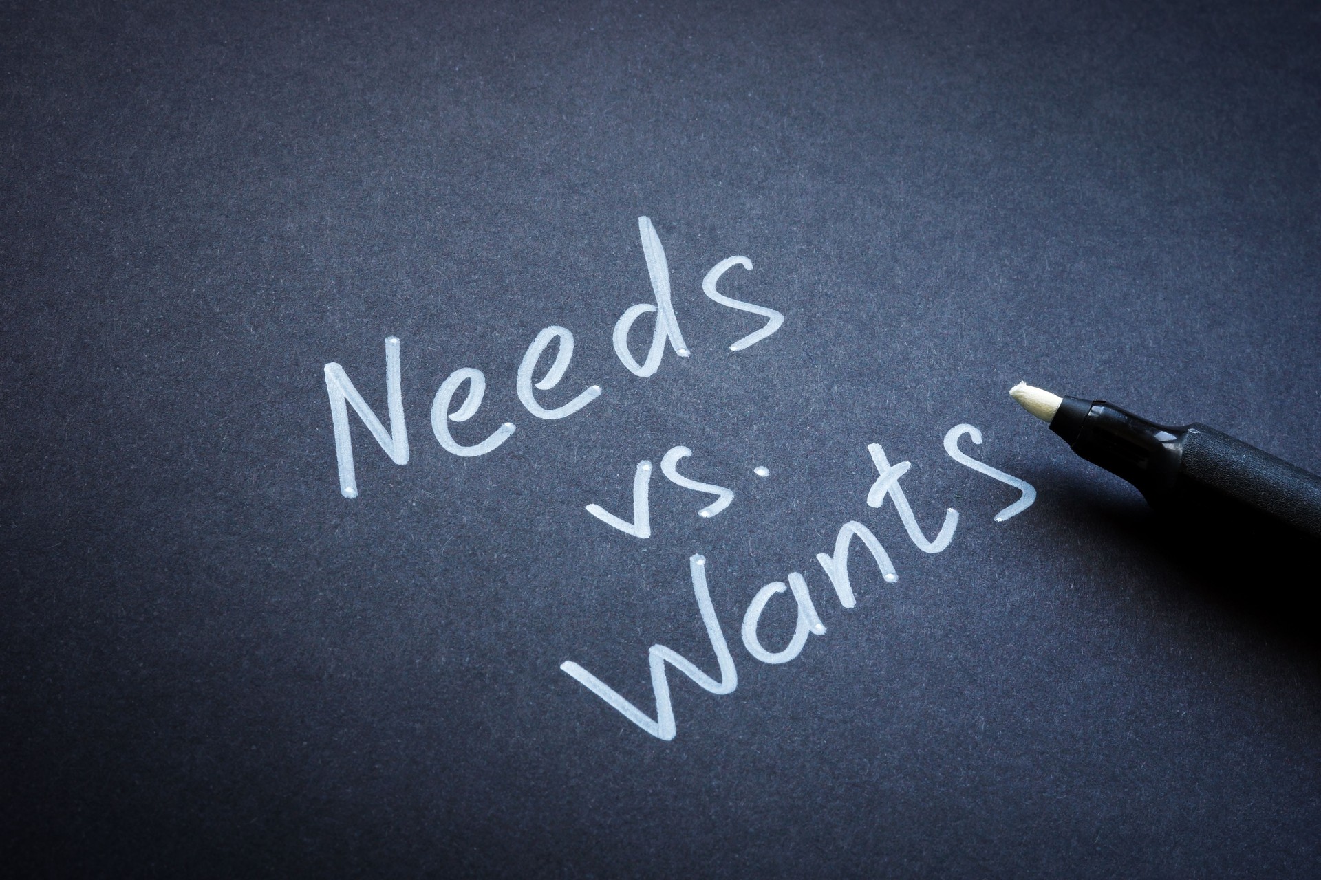 Needs versus wants concept. The inscription on black paper.
